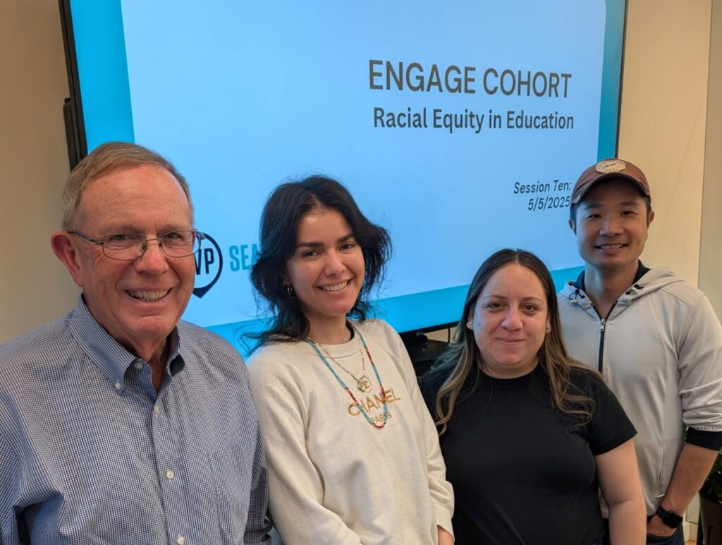Four members of SVP's Engage Cohort standing before a screen that says "Engage Cohort"