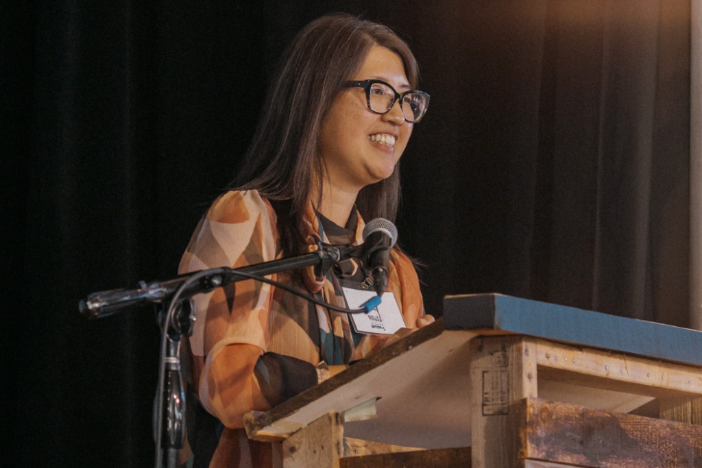 Liz Chang, Executive Director of Unity Collective, smiles as she speaks from the podium during GrowFundMe: Thrive.