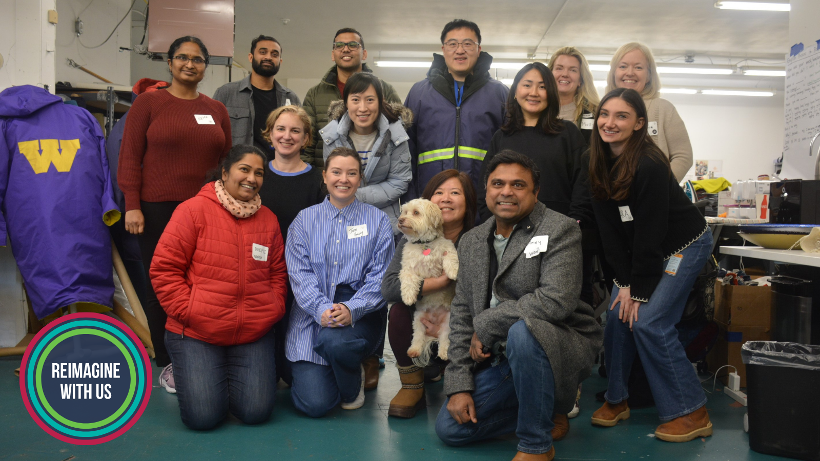 A diverse group of SVP Seattle partners and nonprofit leaders pose together during a visit to Refugee Artisan Initiative, smiling in a workshop space surrounded by creative materials and tools.
